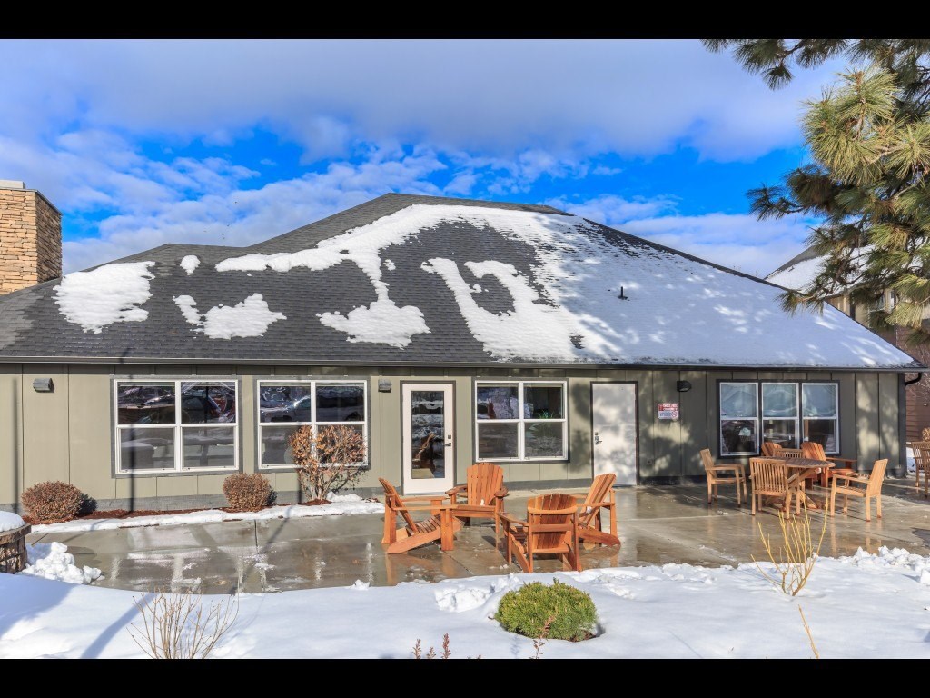 a house with snow on the roof and a patio with chairs